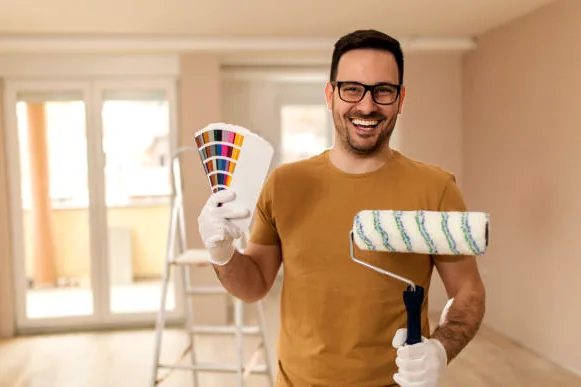 Smiling painter holding a color fan deck and roller
