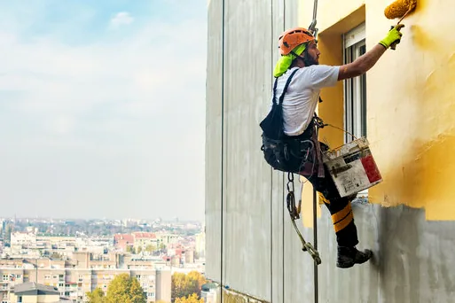 Painter on ropes painting a tall building wall